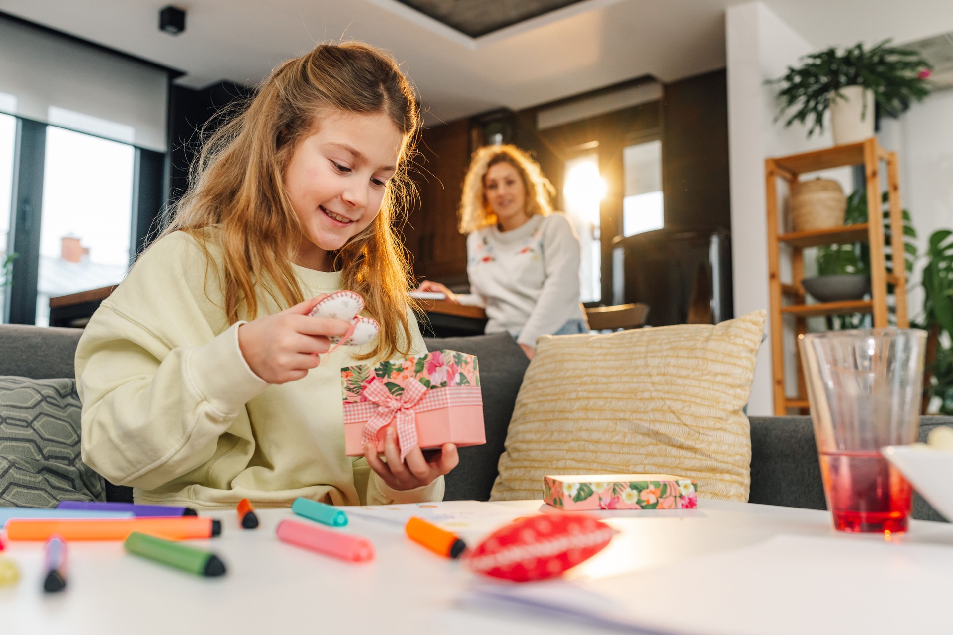 Girl opening handmade gift from mom for mother's day at home